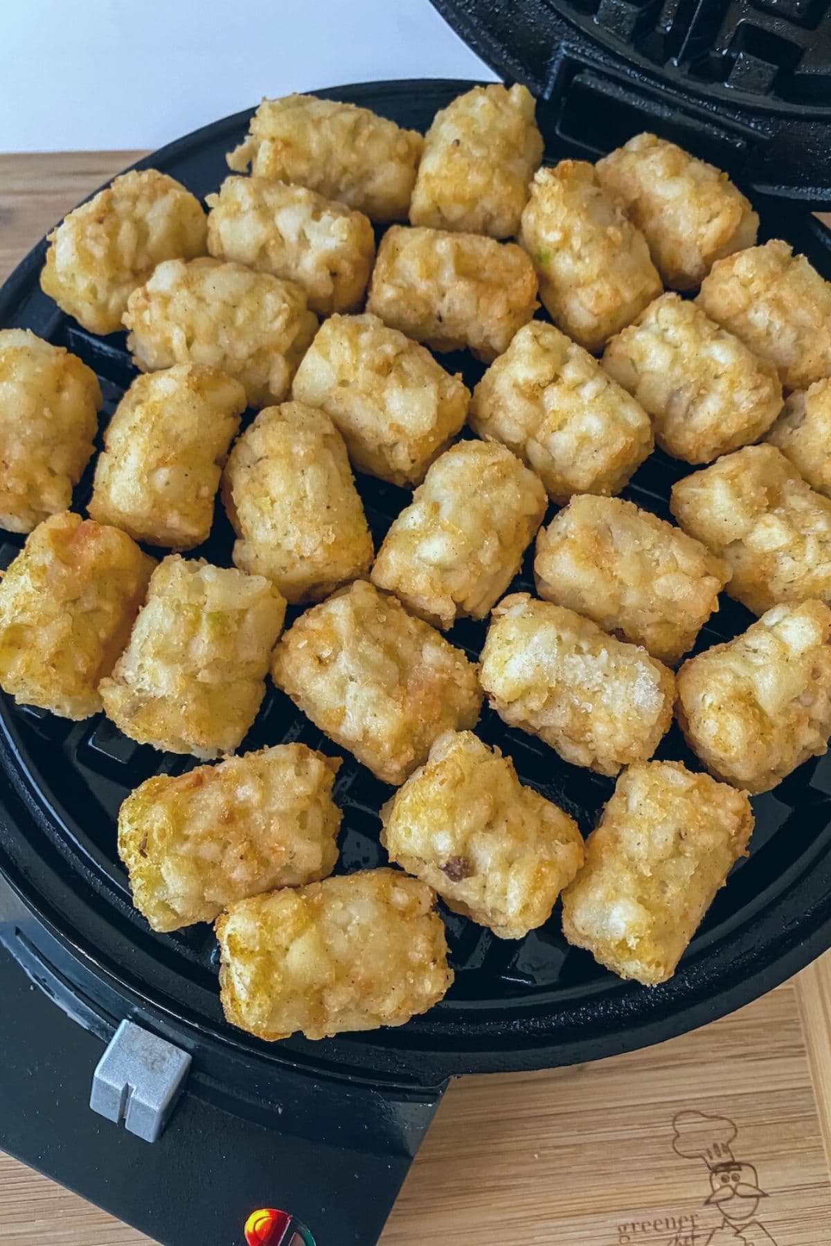 Tater tots spread onto waffle maker