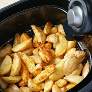 Air fryer potato wedges in black air fryer basket