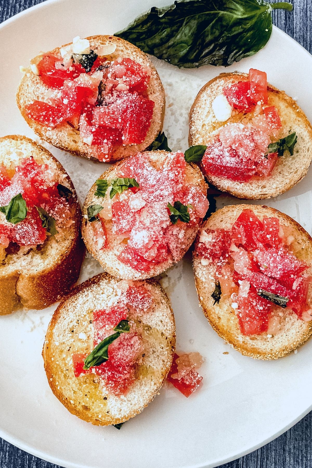 White plate topped with crusty bread and tomato bruschetta