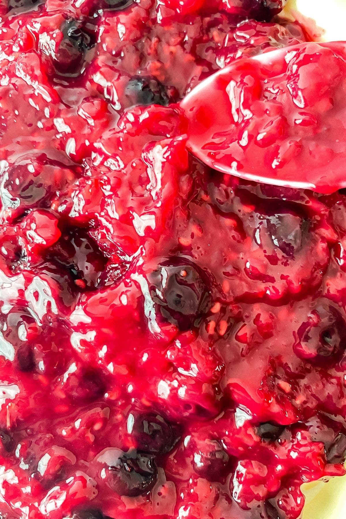 Berry compote spreading with spoon on cake