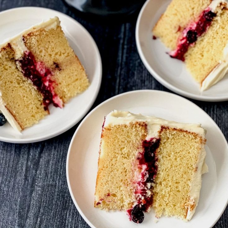 Slices of layer cake with berry filling on white plates