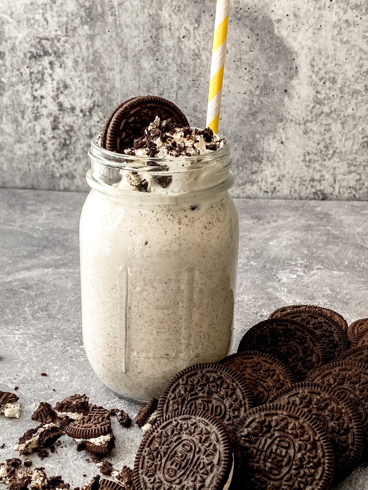 Mason jar with yellow straw filled with ice cream topped with oreo cookie