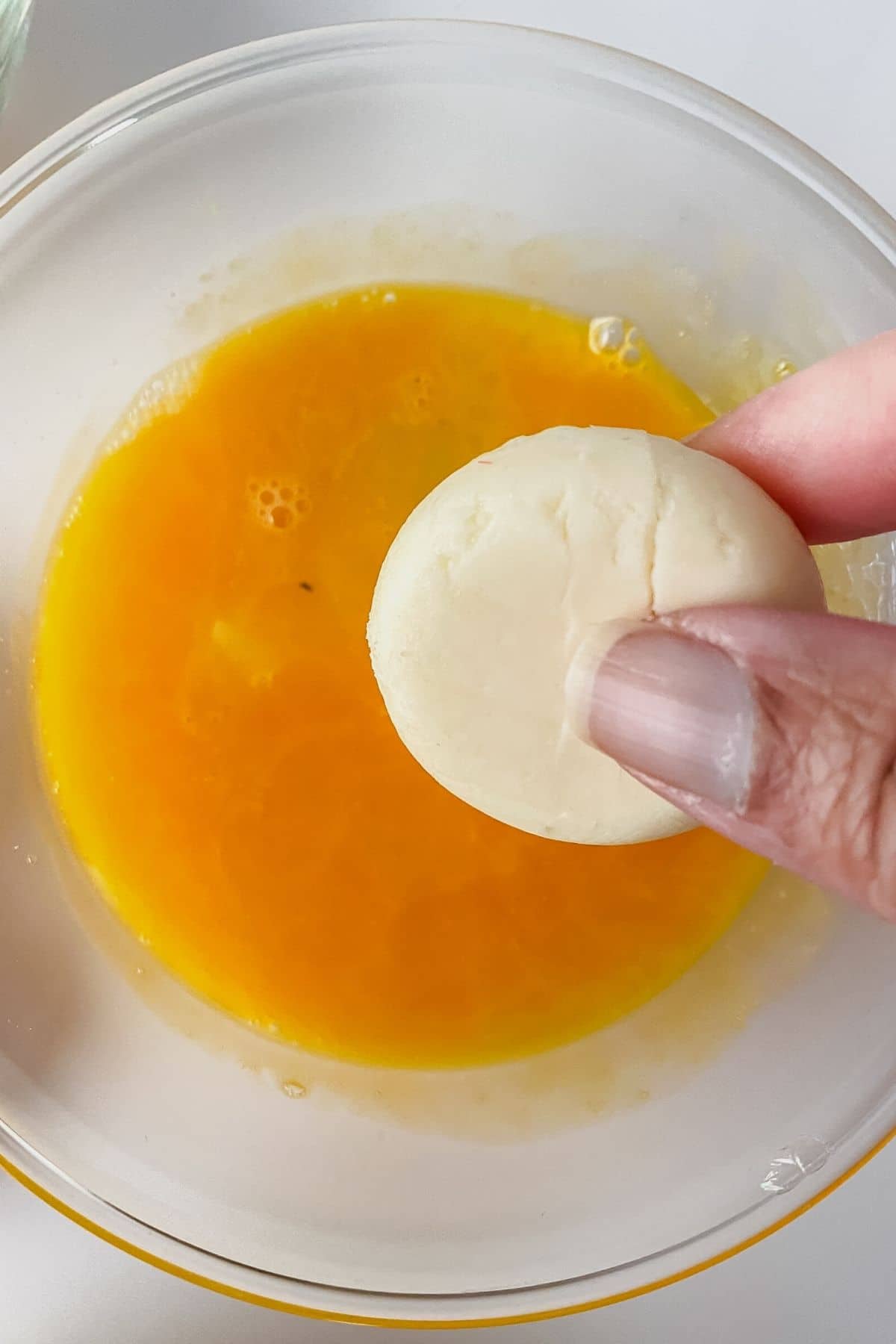 Dipping cheese round into egg