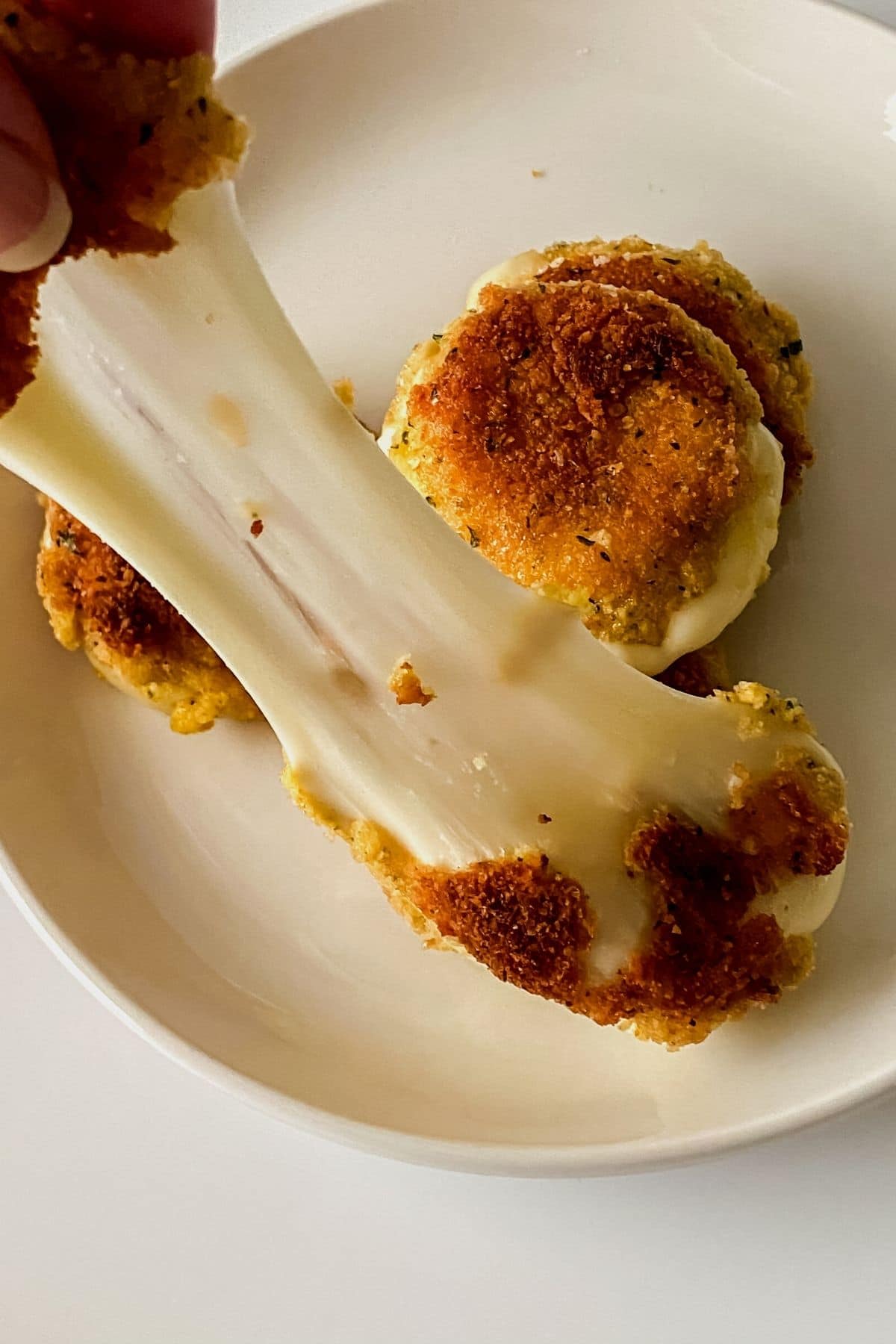 Hand pulling apart fried cheese