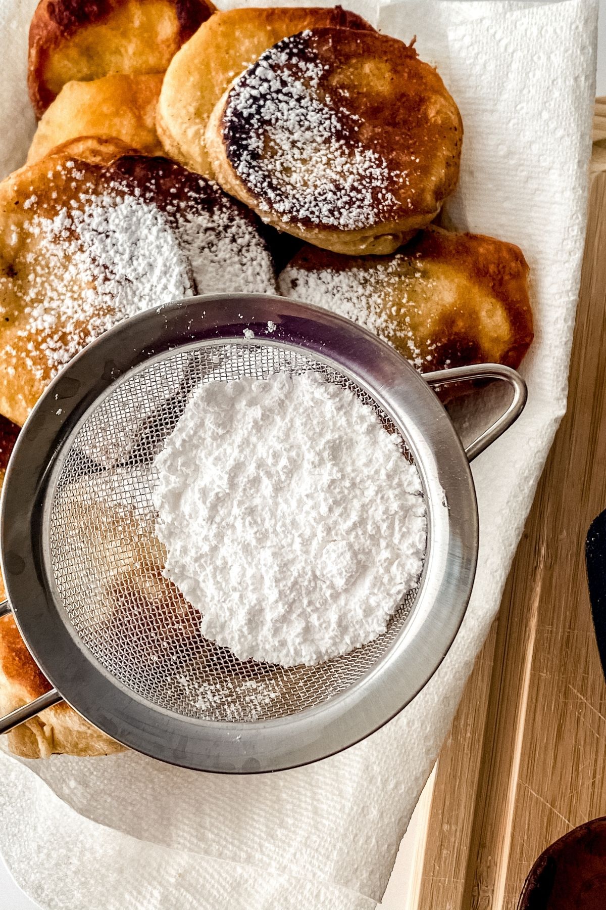 Powdered sugar in sieve over biscuits