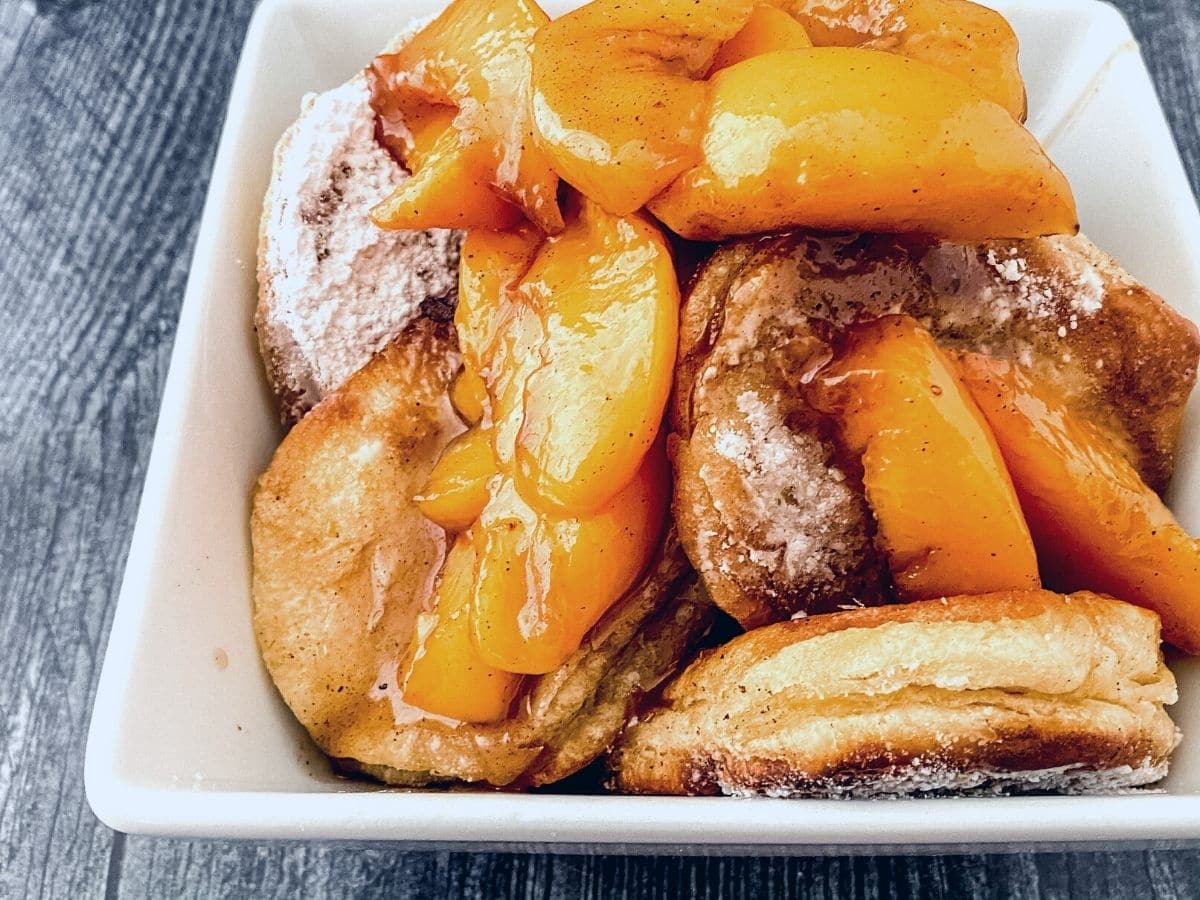 Peaches on top of biscuits in white bowl