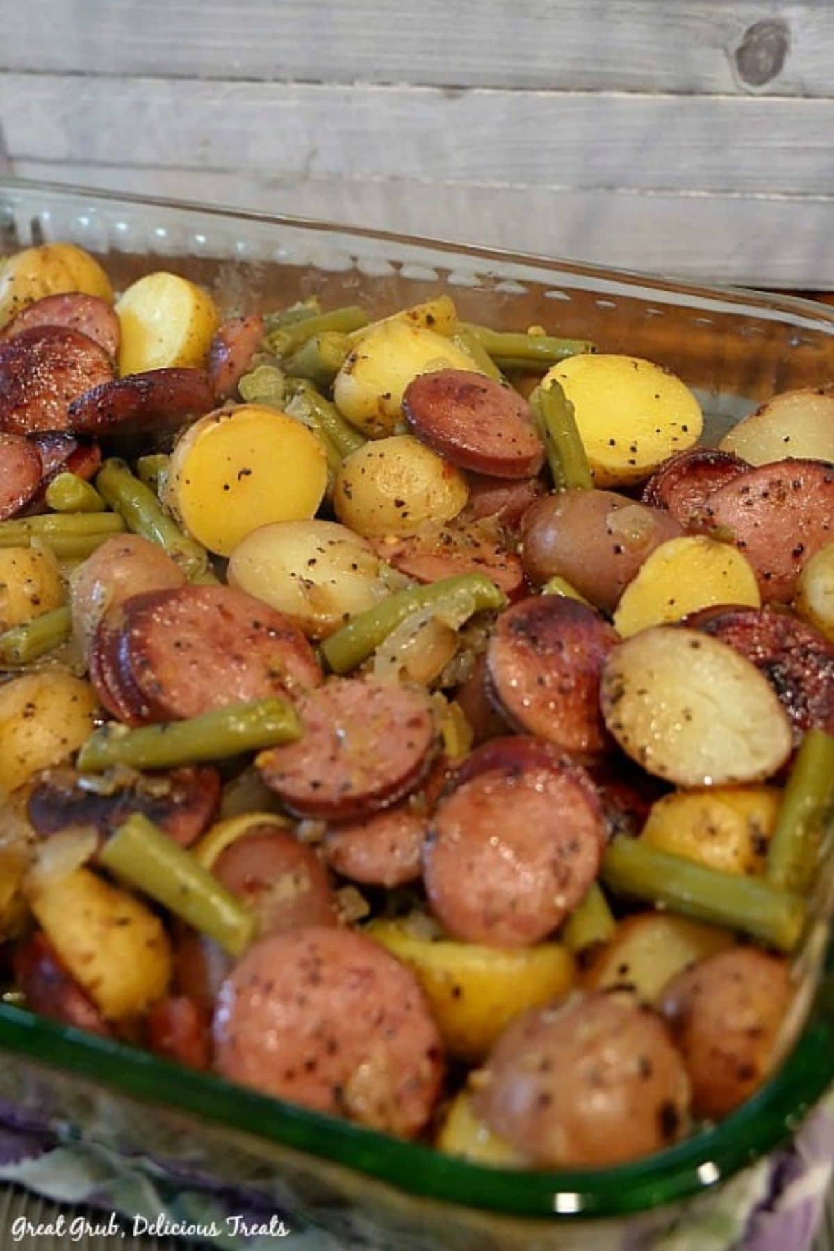 Glass casserole dish filled with sausage potatoes and green beans