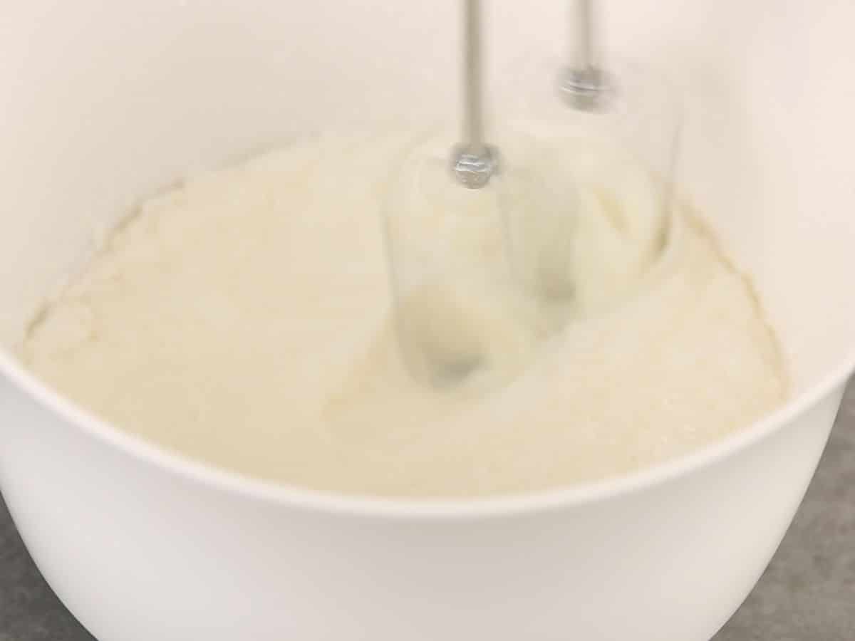 Large white bowl filled with cream being beaten