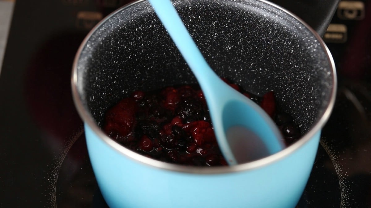 Teal saucepan with berries and blue spoon