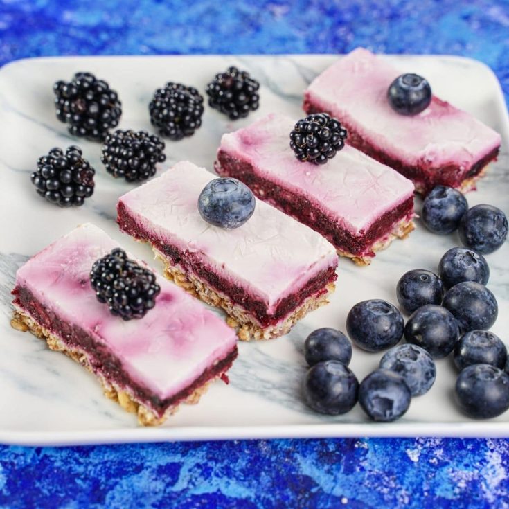 Marble platter on blue table topped with yogurt bars and blueberries
