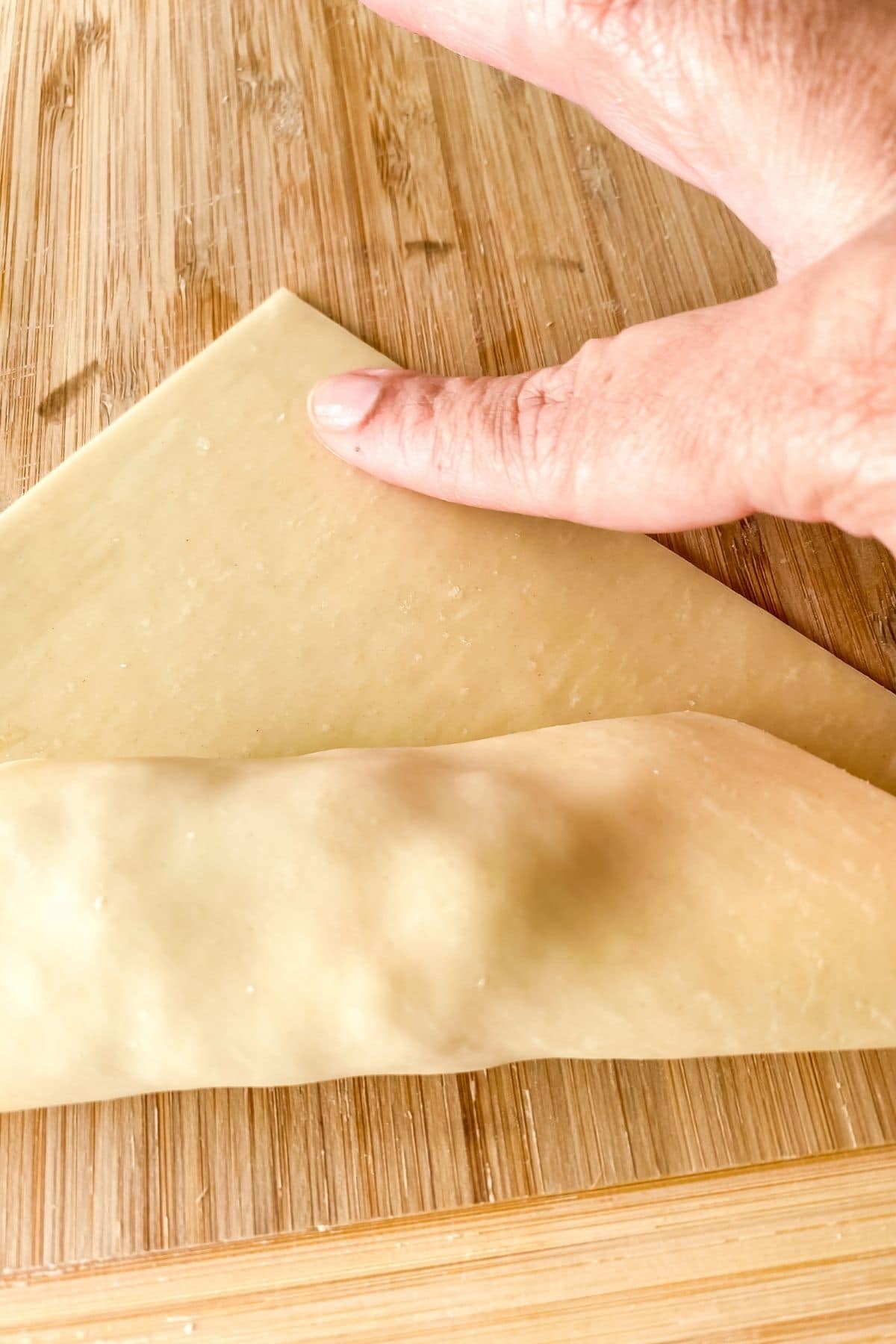 Hand rolling an egg roll on cutting board
