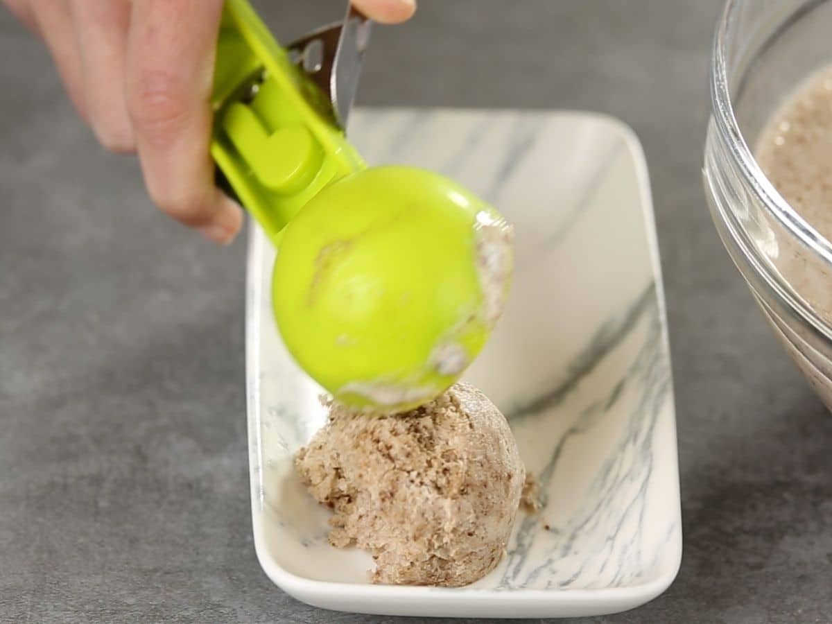 Green ice cream scoop putting chocolate ice cream on marble platter