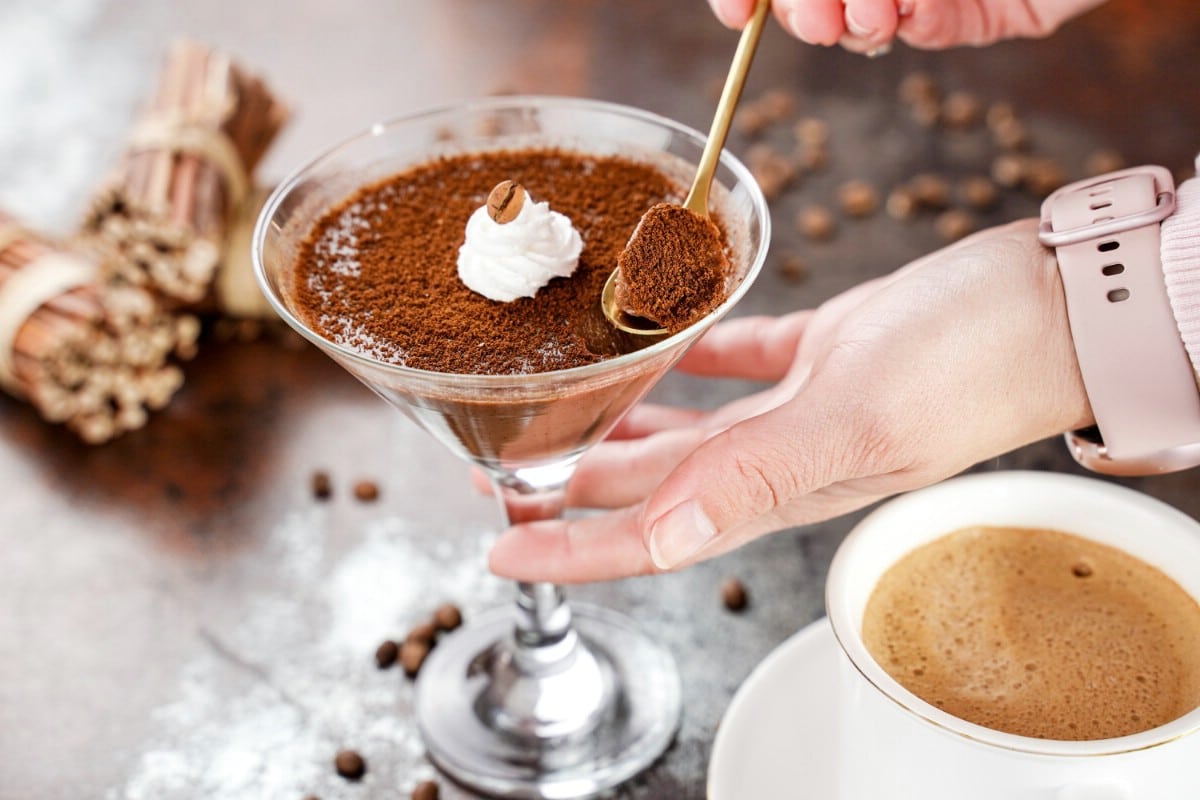 Hand scooping out spoon of chocolate from martini glass