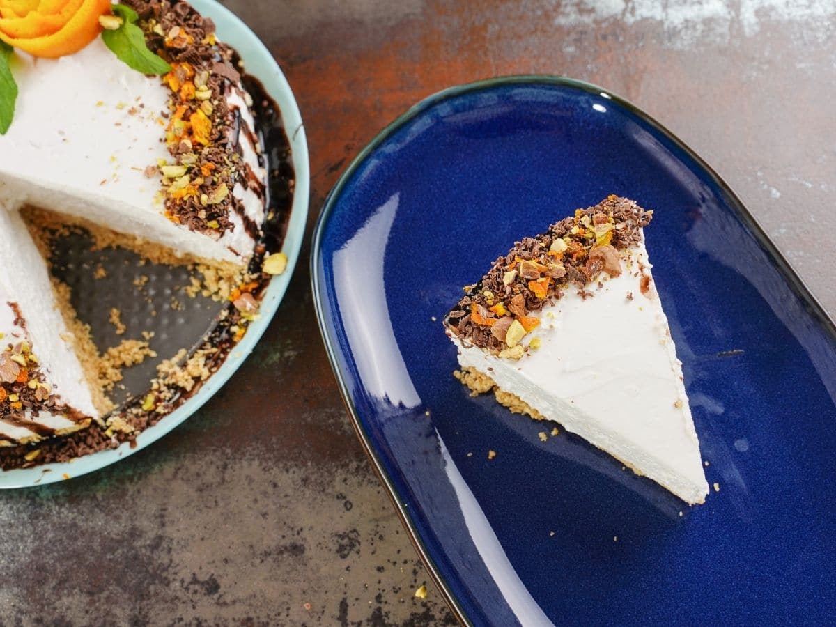 Slice of cheesecake on blue plate sitting on brown table