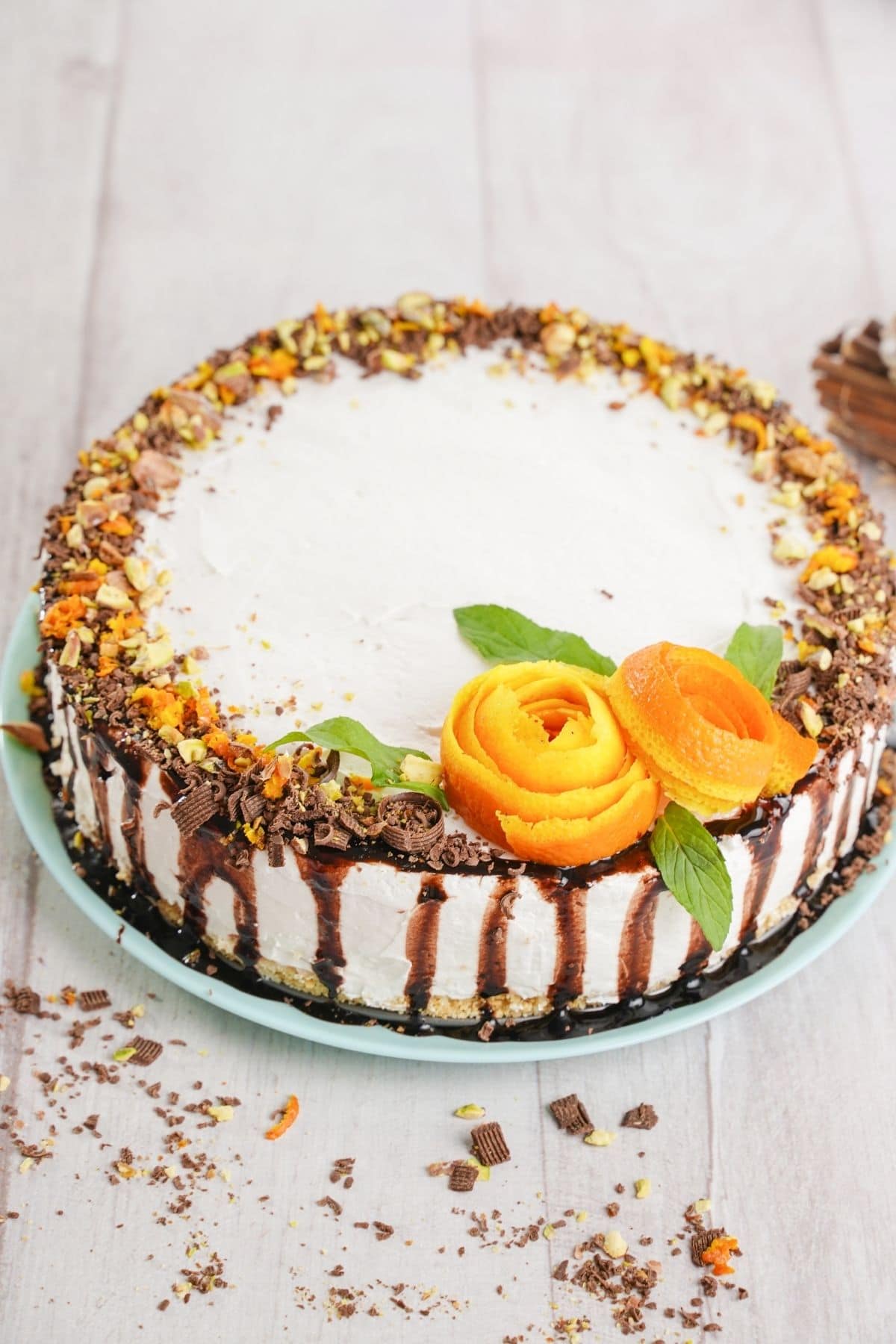 Whole cake topped with orange roses on teal plate on white table