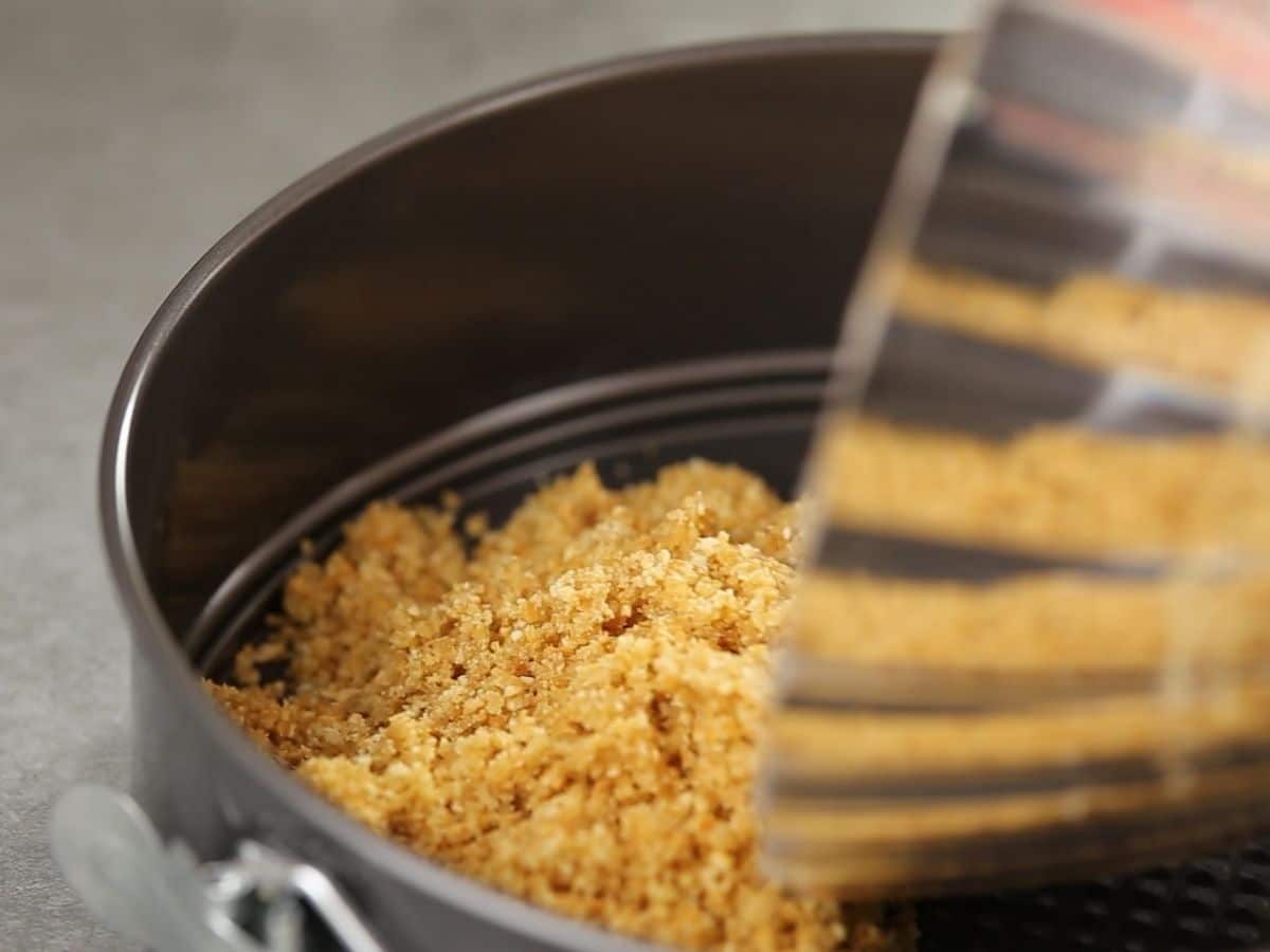 Pouring graham cracker crumbs into springform pan