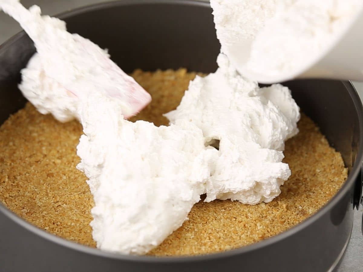 Spreading cream cheese filling into the graham cracker crust in springform pan