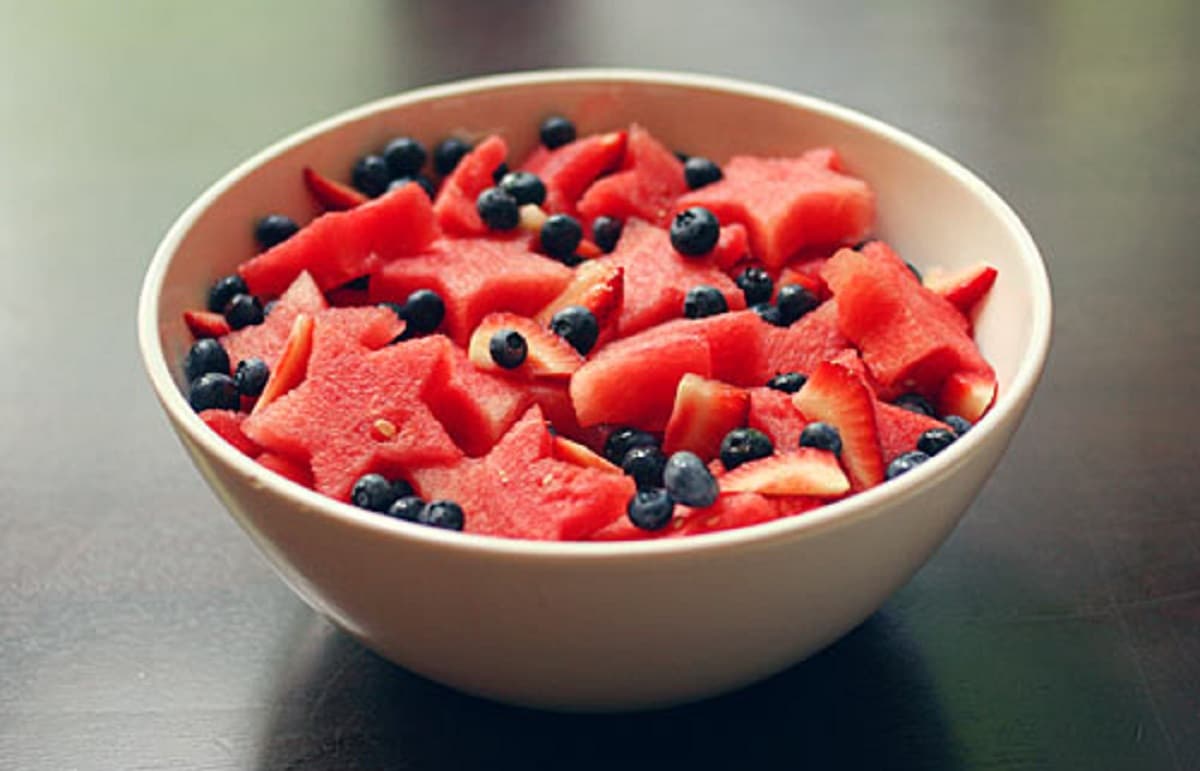 White bowl of star shaped watermelon strawberries and blueberries