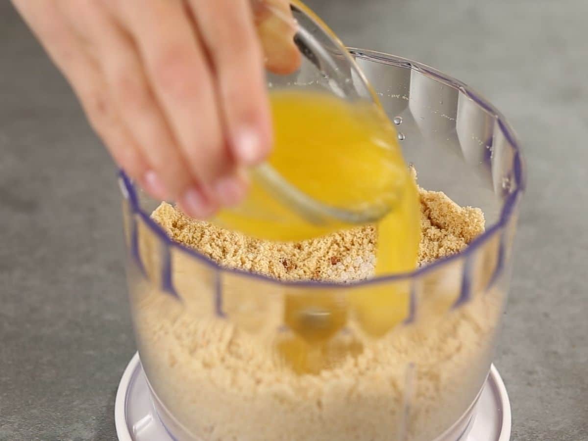Adding butter to cookie crumbs in bowl