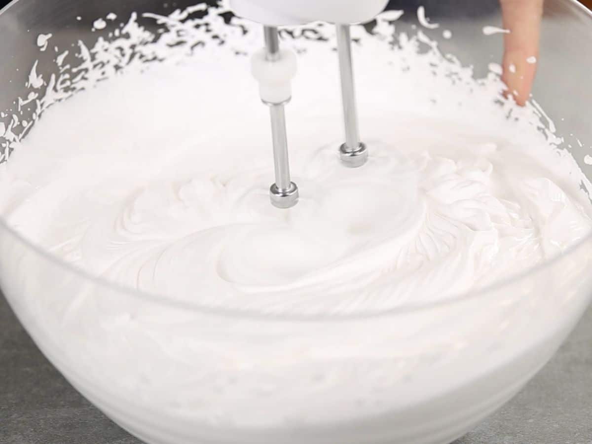 Beaters in whipping cream in glass bowl