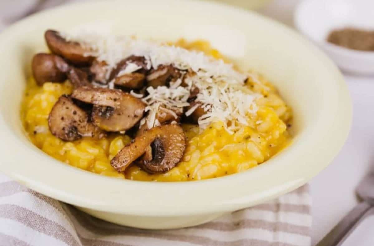 Creamy Pumpkin Risotto topped with parmesan cheese, roasted mushrooms and a dash of olive oil