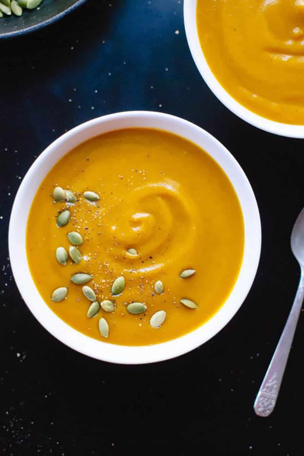 Roasted pumpkin soup made from sugar pie pumpkin, garlic, cinnamon, nutmeg, cloves, cayenne pepper, vegetable broth, heavy cream, maple syrup and topped with toasted pepitas 