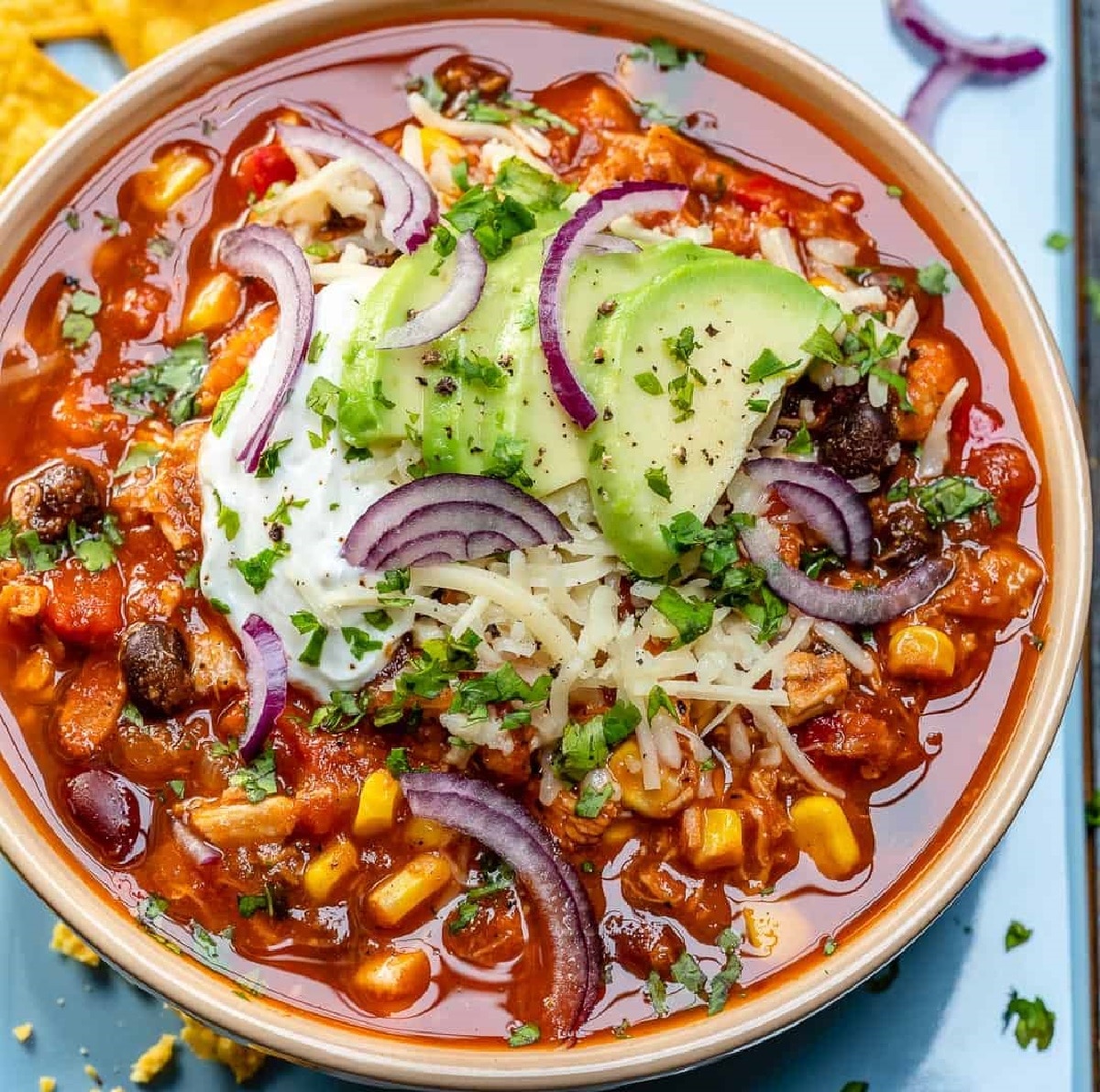 Chicken Chili topped with sour cream, red onions, avocado, and dried oregano