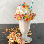 Milkshake in tall glass with Fruity pebbles and whipped cream on top