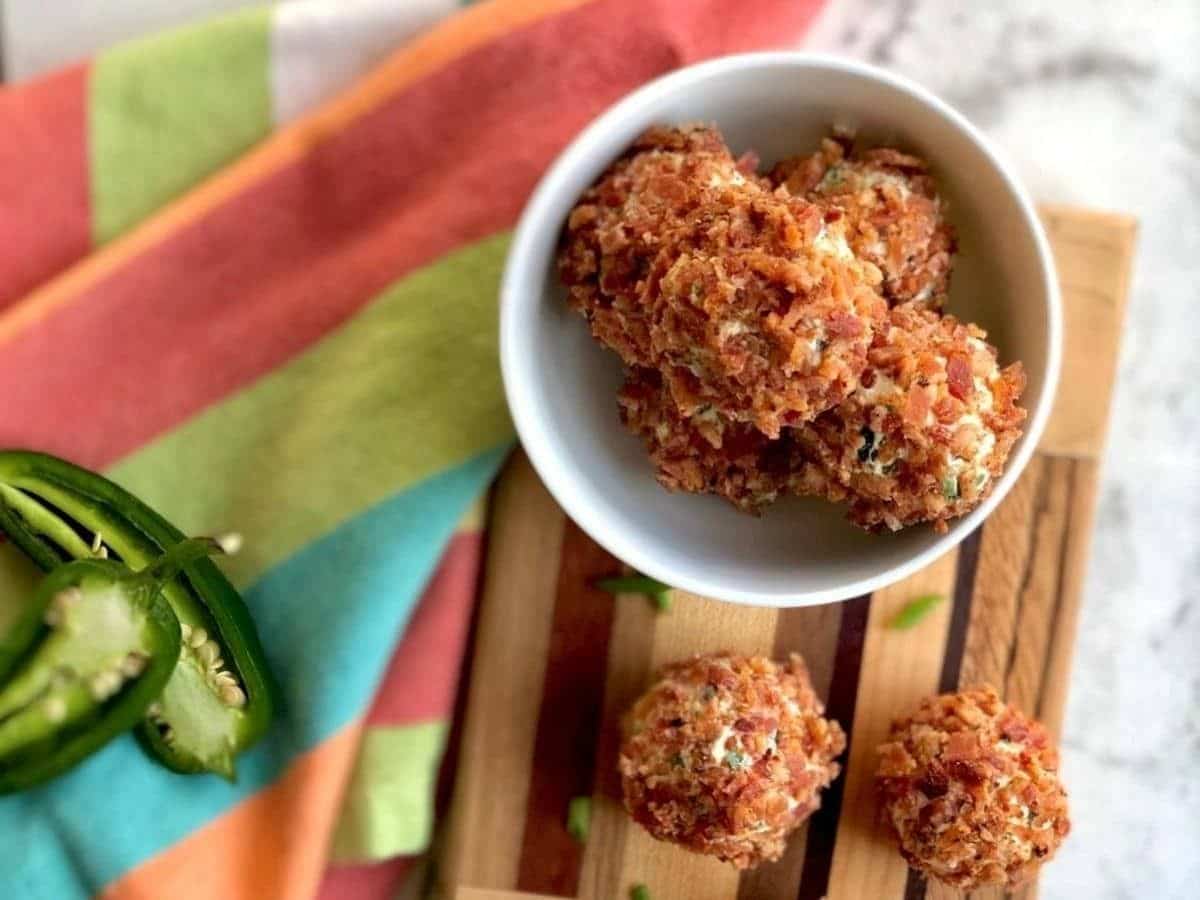 white bowl of jalapeno popper balls on top of cutting board by colorful striped napkin