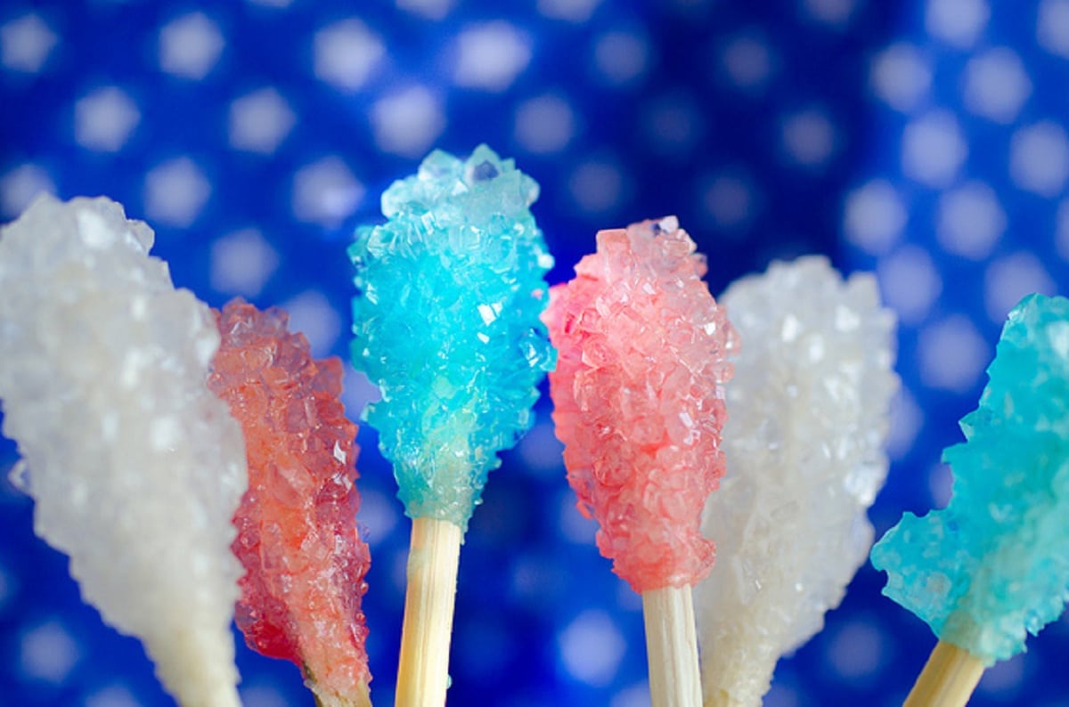 White red and blue rock candy on sticks in front of blue star cloth