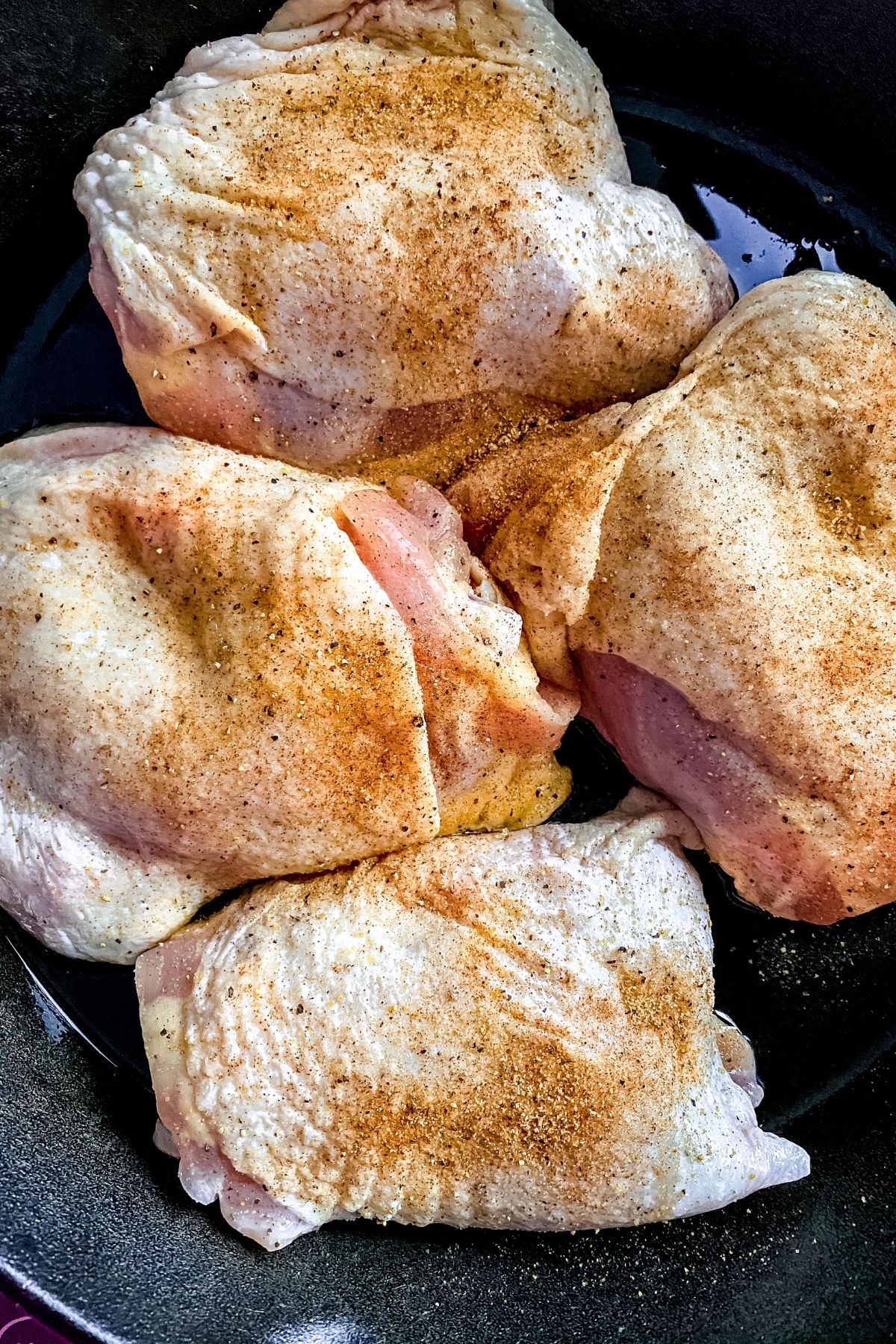 Seasoned raw chicken breasts in cast iron skillet