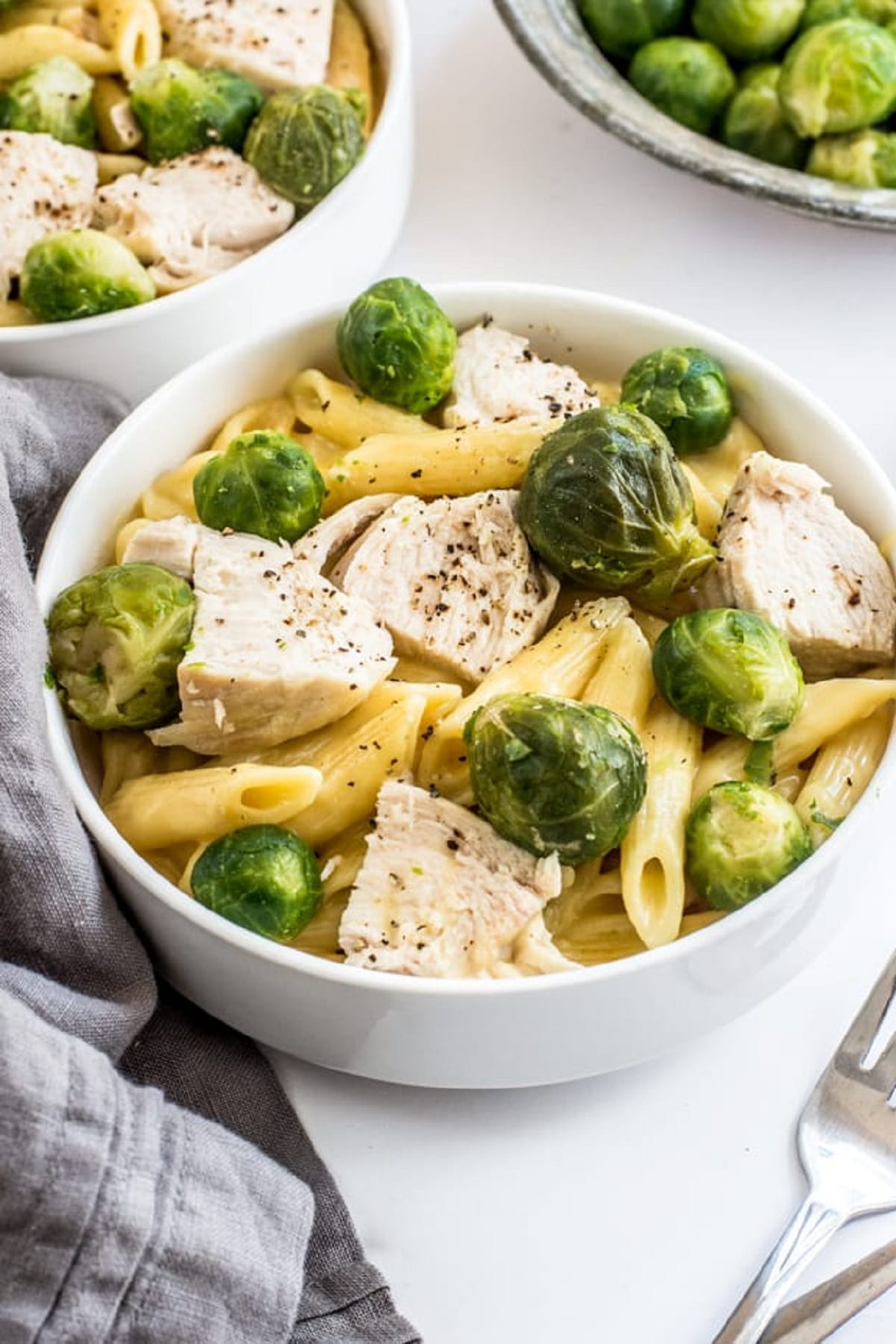 Creamy chicken pasta topped with brussels sprouts and sliced chicken