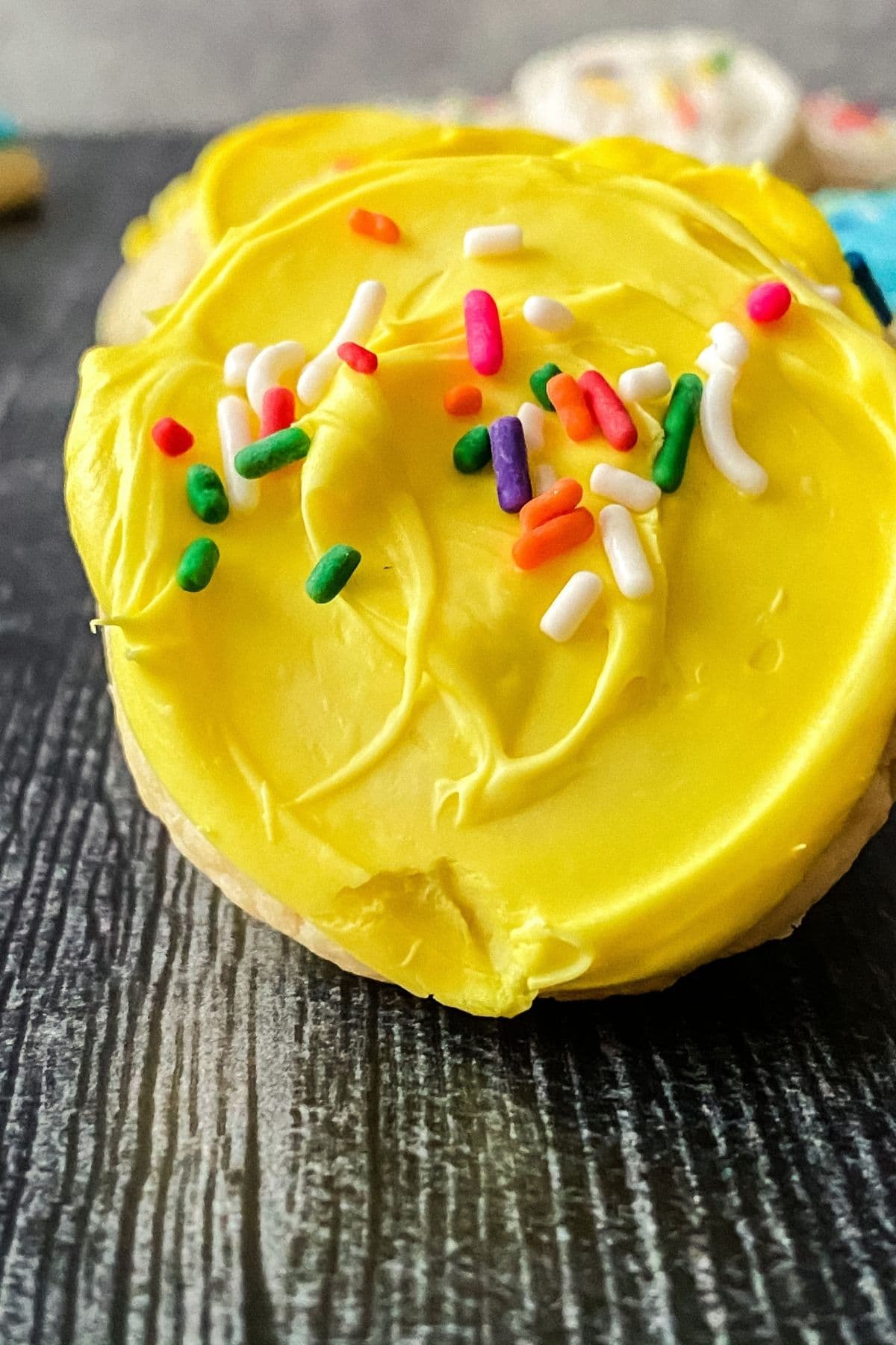 Close up of yellow frosting on cookie with sprinkles