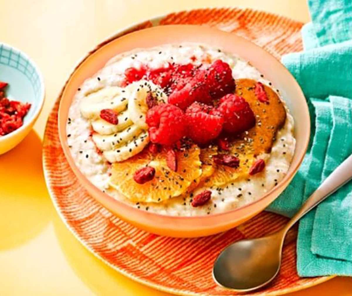 Oatmeal Bowl topped with sliced banana, raspberries and orange slices