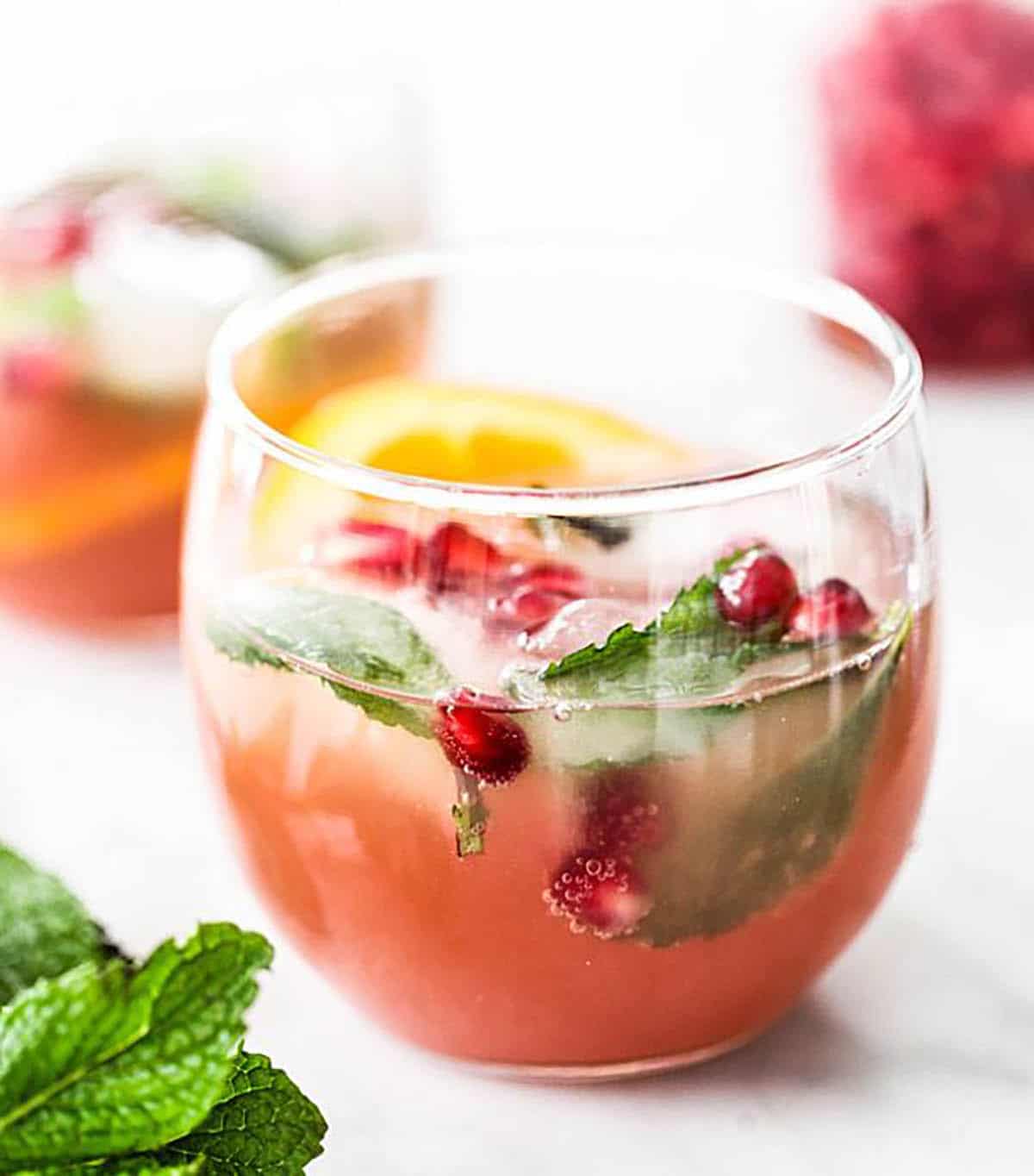 Pomegranate And Orange Champagne Punch with mint and orange wedge