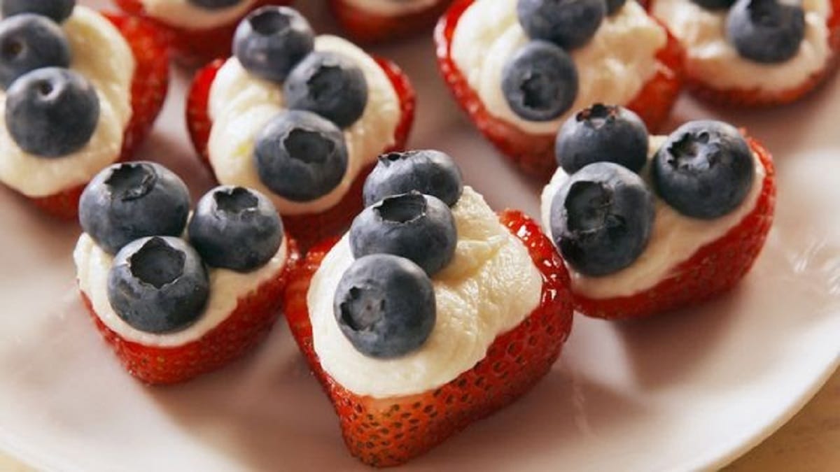 Strawberries on white plate with cream cheese and blueberries on top
