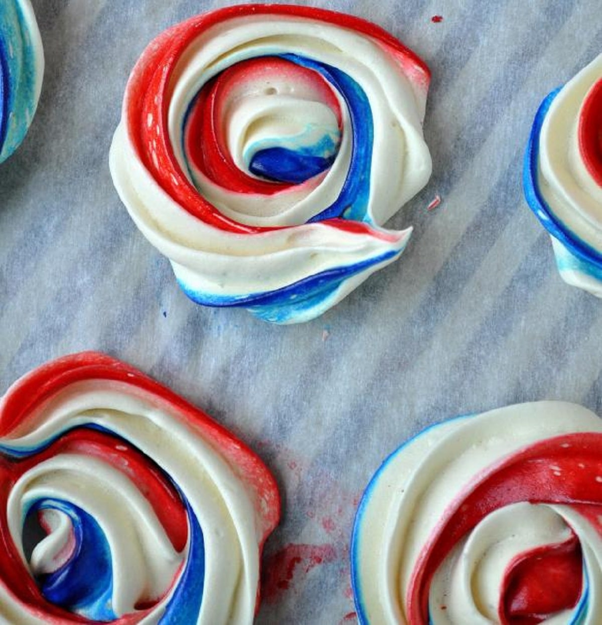Swirls of red white and blue frosting on parchment paper