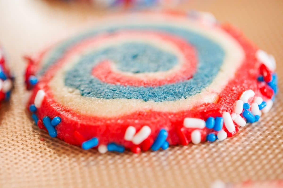 Sliced cookie with swirls of blue and red with red icing and patriotic sprinkles