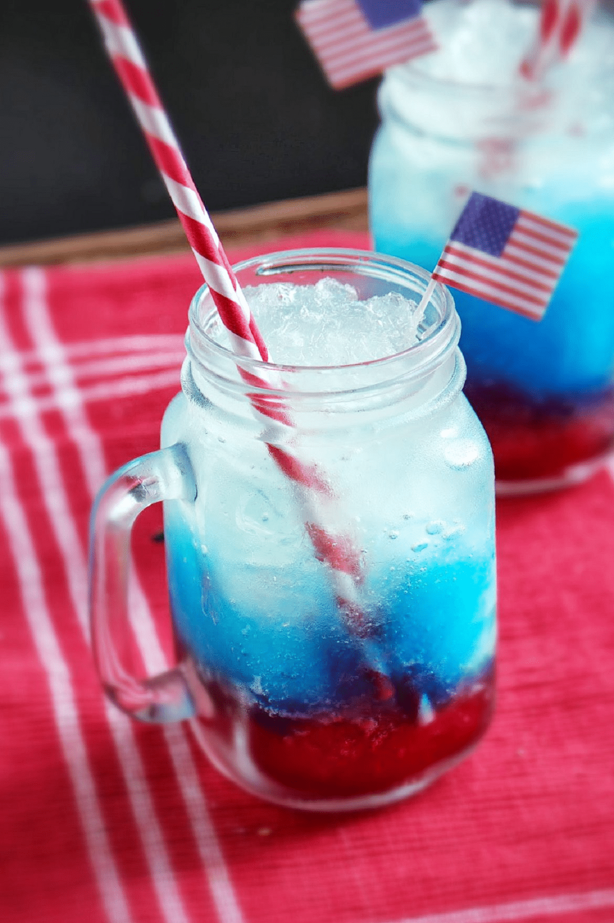 Mason jar mug with red blue and white drink layers and striped straw on red and white striped napkin
