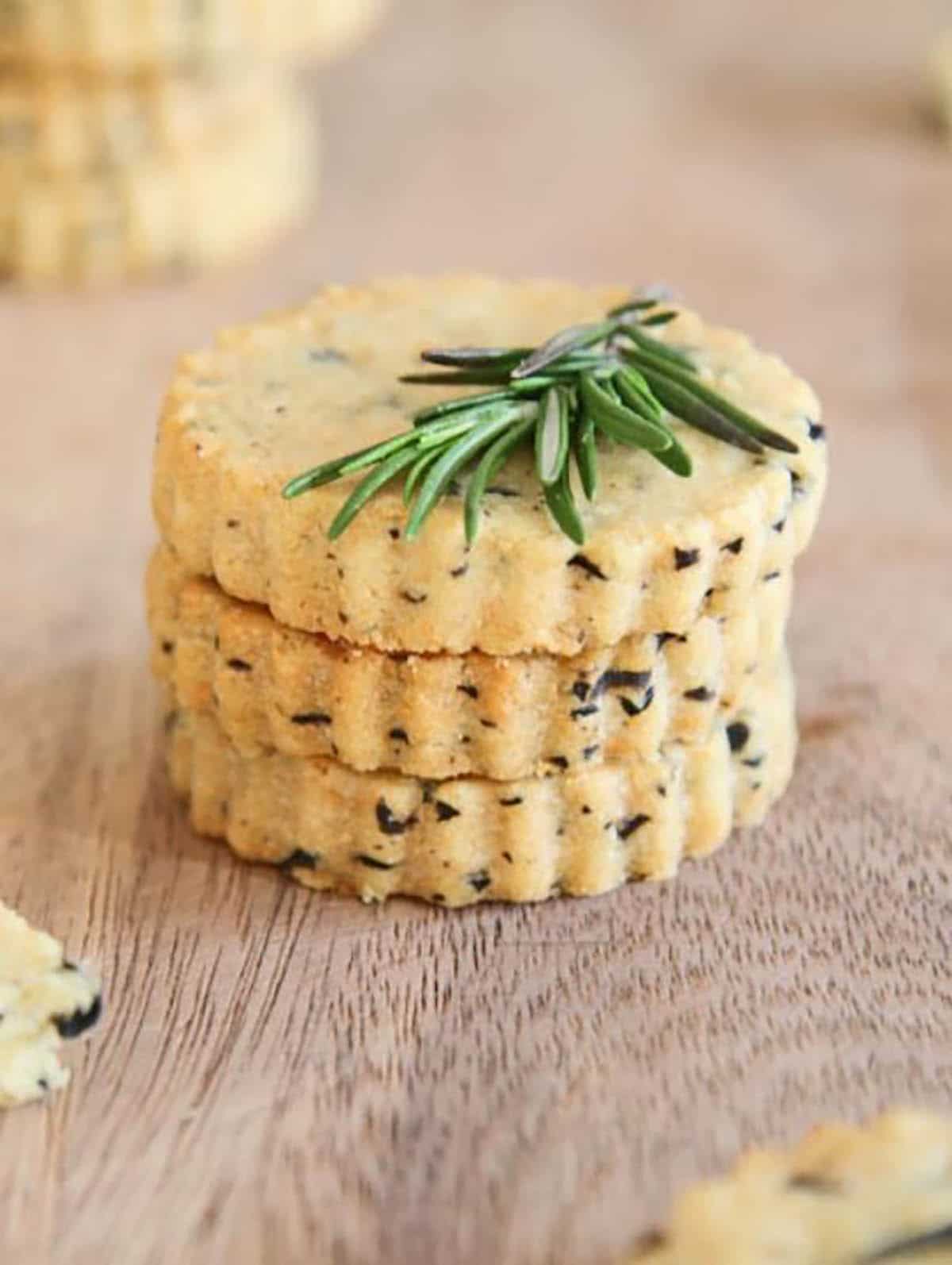Sables made with parmesan cheese, chopped black olives, butter and flour garnished with rosemary
