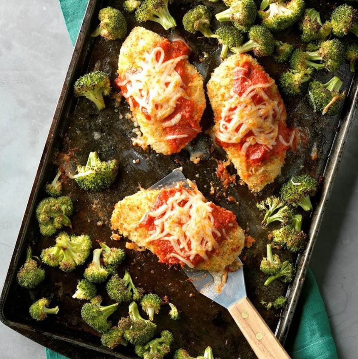 Sheet Pan Chicken Parmesan with broccoli topped with marinara sauce and mozzarella