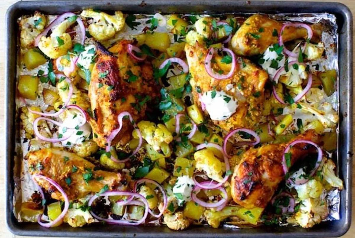 Sheet Pan Chicken Tikka topped with red onions, chopped cilantro and parsley