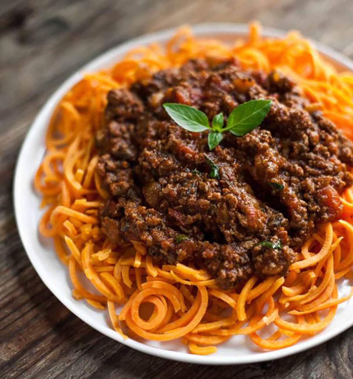 Slow-Cooked Bolognese Sauce with Sweet Potato Spaghetti Garnished with Basil