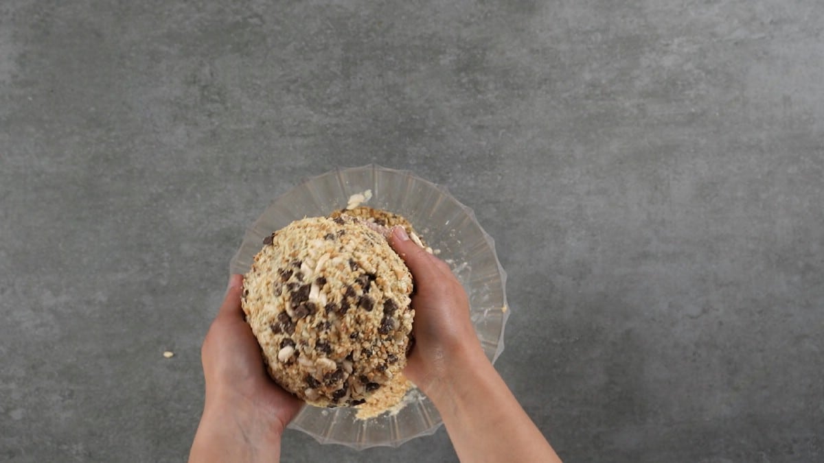 Hand coating cheese ball with chocolate and cracker crumbs