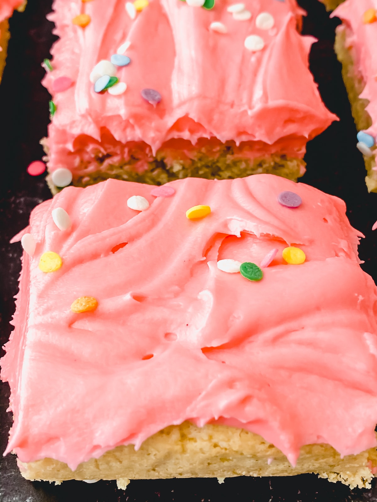 Cookie bars up close with sprinkles on pink icing