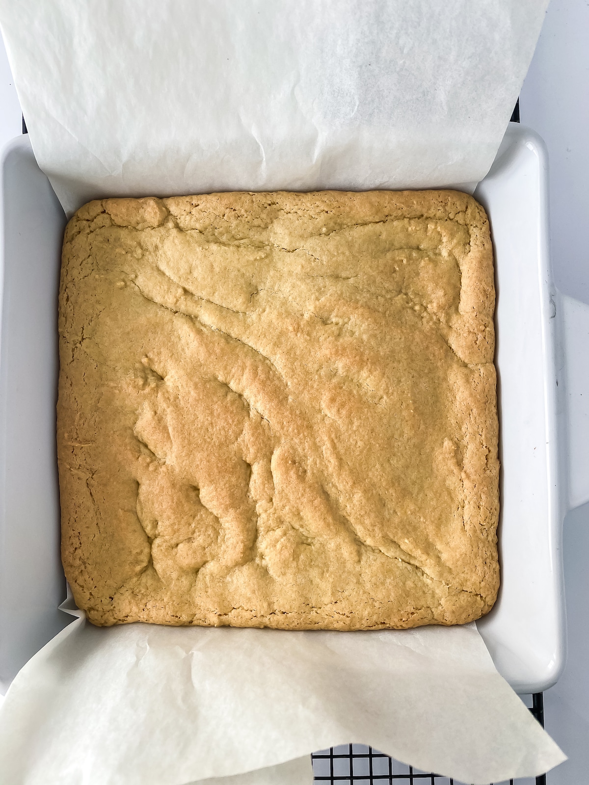 Square white pan with baked cookie on parchment paper