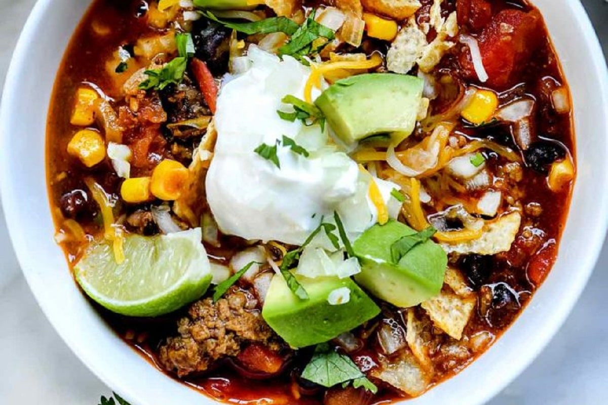A bowl of Taco Soup with lime, avocado slices