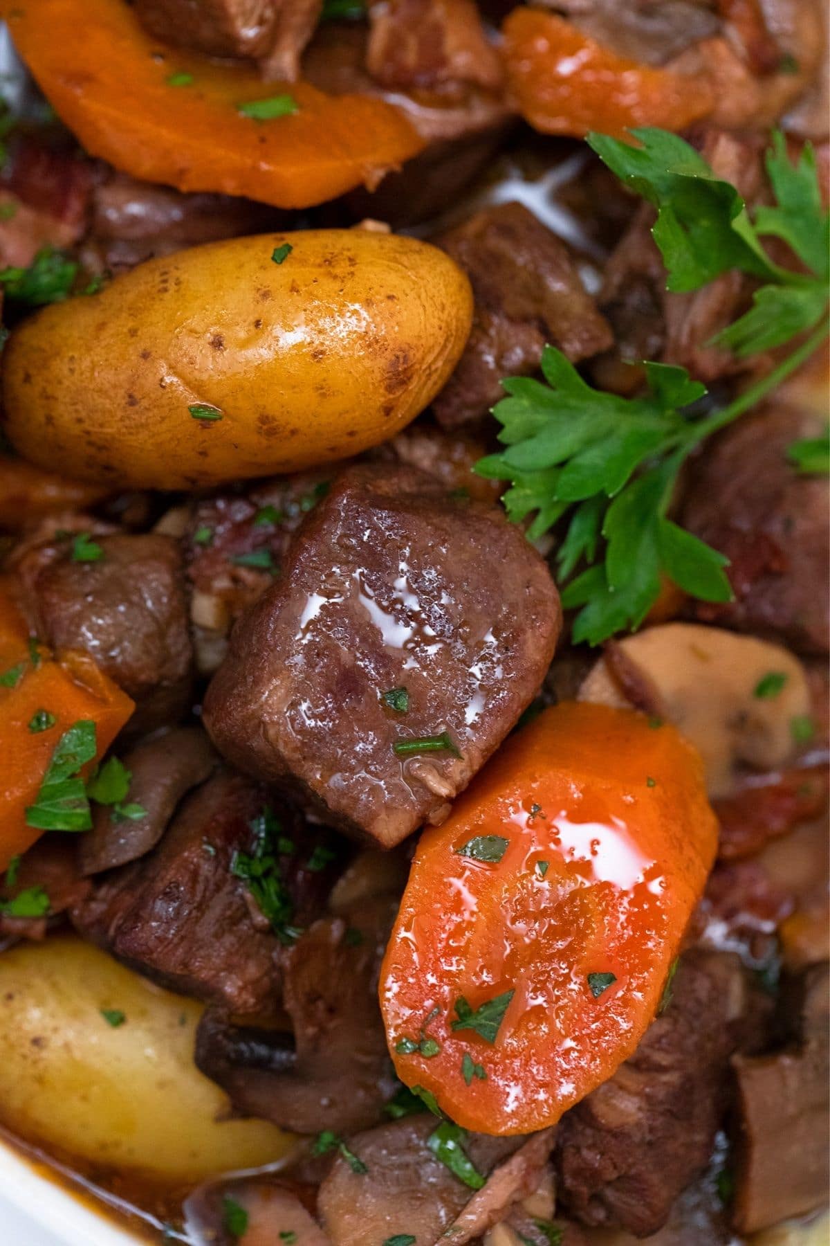 Close up picture of beef chunks with carrots and baby potatoes and parsely