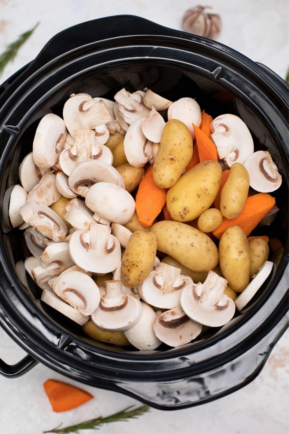 Round black crock filled with mushrooms potatoes and carrots