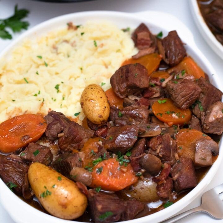 Large white bowl of potatoes and beef with carrots